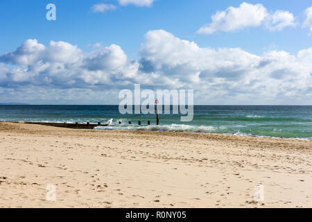 Vista di Bournemouth Beach in autunno con onde che si infrangono su un groyne & fluffy cumulus nuvole in una giornata di sole, Dorset, Regno Unito Foto Stock