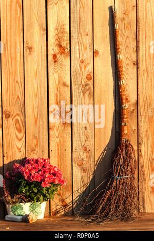 Vecchio empi scopa la parete in legno . La strega scopa. Luce della Sera. Decorazione sulla terrazza. La vita in azienda Foto Stock