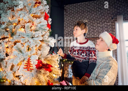 Una famiglia felice decora un albero di Natale a casa. Foto Stock