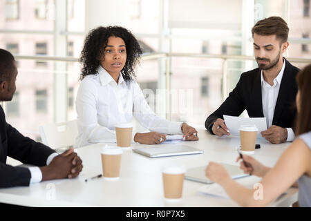 Multirazziale colleghi negoziare durante il briefing in office Foto Stock