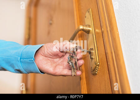 Uomo senior di bloccaggio porte con chiave in mano Foto Stock