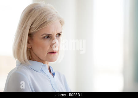 Riflessivo di mezza età imprenditrice guarda nella distanza ponderando Foto Stock