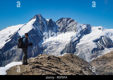 Escursionista sulla cima di Mt. Fuscherkarkopf davanti la montagna più alta dell'Austria Grossglockner, Parco Nazionale Hohe Tauern Foto Stock