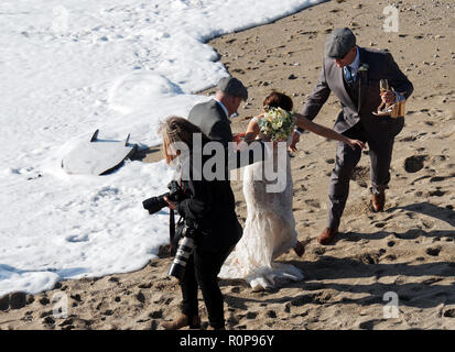 Sposa catturati da onda sulla spiaggia, Newquay, Cornwall, Regno Unito. Foto Stock