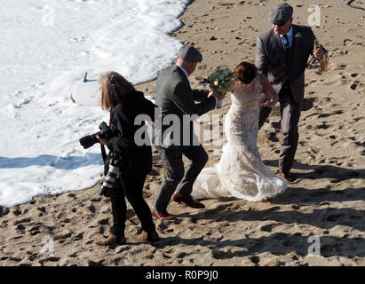 Sposa catturati da onda sulla spiaggia, Newquay, Cornwall, Regno Unito. Foto Stock