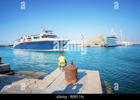 Fisherman accanto all'ingresso nel porto di Mandraki nella città di Rodi (Rhodes, Grecia) Foto Stock