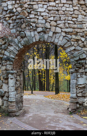 Autunno alberi vista attraverso l'arco nel vecchio muro di pietra in Kuskovo museo-riserva. Sfondo con copyspace Foto Stock