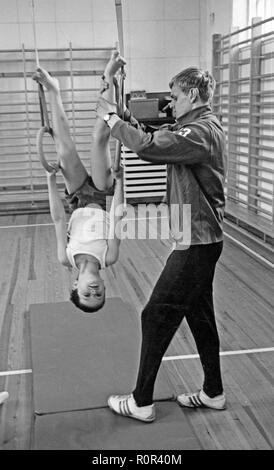 Scuola ginnastica negli anni settanta. Un insegnante è aiutare un giovane ragazzo bilanciamento durante la classe di ginnastica. La Svezia degli anni settanta Foto Stock