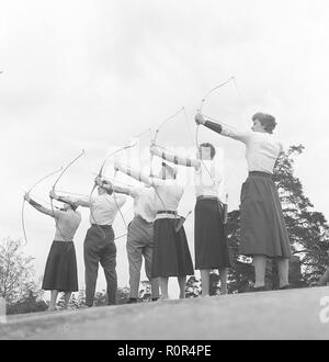 Tiro con l'arco negli anni '1950s. Un gruppo di uomini e donne sta in piedi con le loro archi e frecce, puntando a un bersaglio. Svezia 1957. Foto Kristoffersson Ref BY47-6 Foto Stock