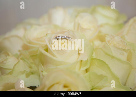 Close up di diamante anello di fidanzamento in spose bouquet di rose di crema il giorno del matrimonio prima di lei ottiene sposato Foto Stock