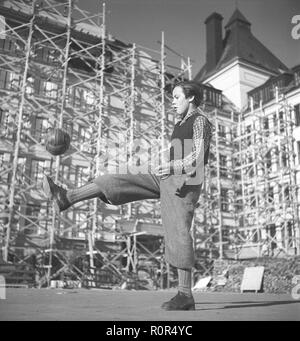 1940s ragazzo giocando a calcio. Un ragazzo vestito in tipico degli anni quaranta pantaloni sta giocando con il suo calcio nel cortile della scuola. La Svezia negli anni quaranta Foto Kristoffersson ref AE25-10 Foto Stock