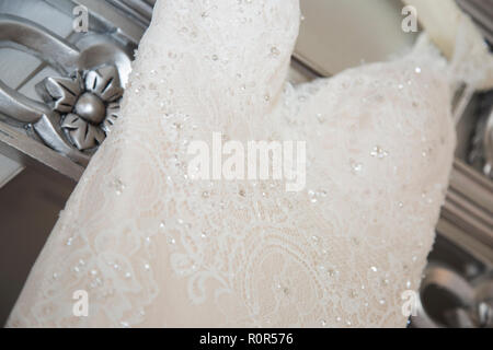 Close up di un abito da sposa appendere su un argento letto a baldacchino Foto Stock