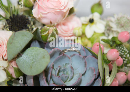 Bouquet di nozze di diamante con anello di fidanzamento annidato in fiori in attesa di essere indossato dalla sposa che il giorno del matrimonio Foto Stock