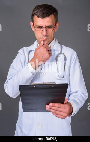 Uomo bello medico con capelli corti contro uno sfondo grigio Foto Stock