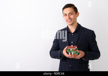 Studio shot di giovani happy businessman sorridente tenendo hou Foto Stock