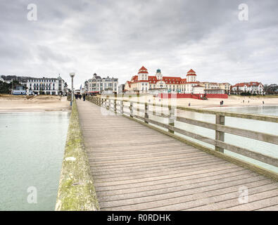 Binz sull isola di Ruegen, Germania. Il 27 gennaio 2018. Kurhaus Spa edificio con la famosa promenade, ponte di mare, la spiaggia di sabbia con i turisti. Foto Stock