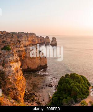 Tramonto sul mare costa rocciosa di arenaria, formazioni rocciose nel mare, Algarve, Lagos, Portogallo Foto Stock