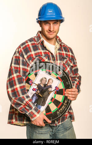 Aggressivo builder tenendo un dartboard con foto dei suoi clienti su CI Foto Stock