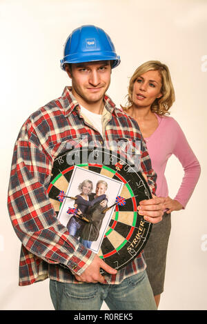 Aggressivo builder tenendo un dartboard con foto dei suoi clienti su CI Foto Stock