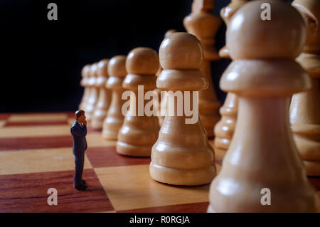 Gli imprenditori in miniatura battaglia con chesspieces gigante per la metafora simbolica Foto Stock