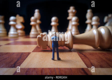 Gli imprenditori in miniatura battaglia con chesspieces gigante per la metafora simbolica Foto Stock