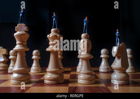 Gli imprenditori in miniatura battaglia con chesspieces gigante per la metafora simbolica Foto Stock