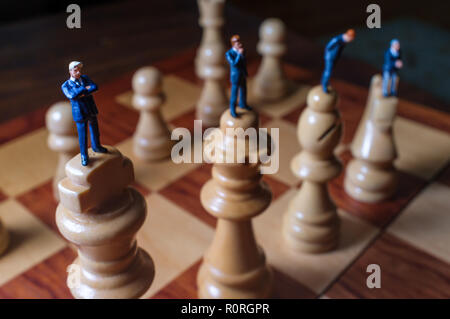 Gli imprenditori in miniatura battaglia con chesspieces gigante per la metafora simbolica Foto Stock