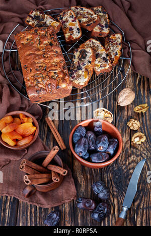 Vista aerea del delizioso chunky frutta secca ricca torta su un filo cake stand con panno marrone, bastoncini di cannella, albicocche secche e data la frutta in una r Foto Stock