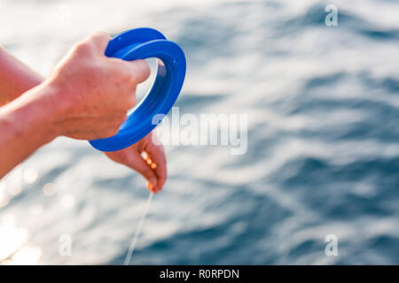 Ben utilizzato linea di mano e il mulinello da pesca in mare tropicale. Sfocata sullo sfondo del mare. Acqua relativa allo sport e al tempo libero lo sfondo Foto Stock