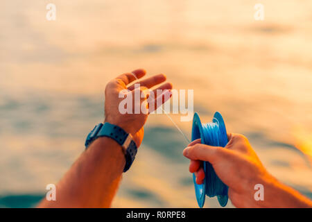 Ben utilizzato linea di mano e il mulinello da pesca in mare tropicale. Sfocata sullo sfondo del mare. Acqua relativa allo sport e al tempo libero lo sfondo Foto Stock