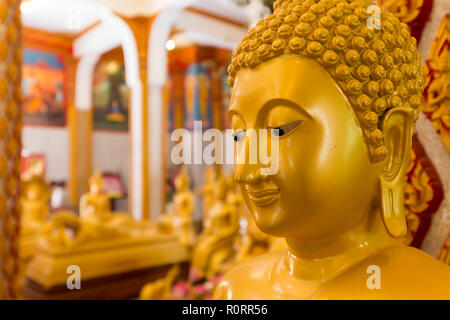 Chiudere su un tradizionale Buddha volto di una statua dorata in Wat Chalong tempio, Phuket, Tailandia Foto Stock