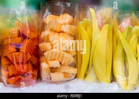 Mango fresco, melone e papaia frutti tagliati a fette in borse di plastica in un mercato di strada. Foto Stock