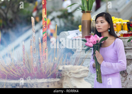 Donna buddista pregando nel tempio, tenendo lotus boccioli di fiori mazzetto, Vietnam Foto Stock