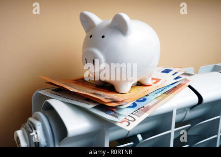 Salvadanaio e le banconote in euro sul radiatore di riscaldamento. Foto Stock