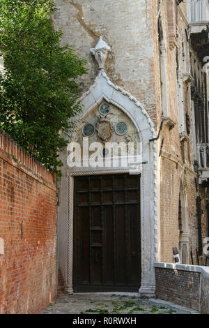 Venezia, lo sportello di un antico palazzo, con decorazioni in marmo e un muro di mattoni Foto Stock