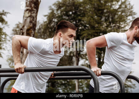 Due sportivi facendo dips su barre parallele Foto Stock