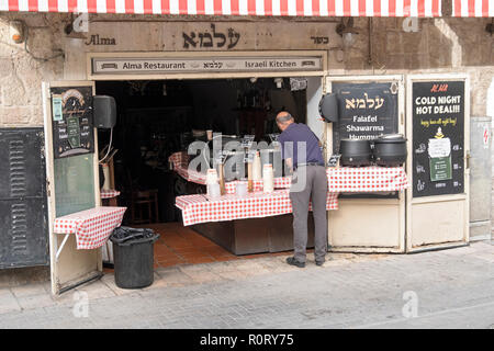Un lavoratore o forse il titolare del ristorante Alma su Yosef Rivlin San in Gerusalemme apre le sue porte e si prepara per il pranzo folla. Foto Stock