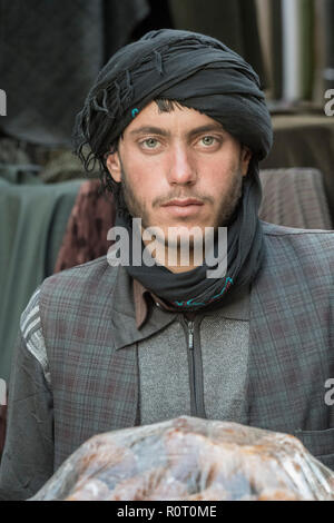 Giovane macellaio indossando un turbante nero con carne di fronte a lui a Mazar-e Sharif Central Bazaar, Maraz-e Sharif, Balkh Provincia, Afghanistan Foto Stock