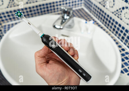 Elettrico spazzolino ricaricabile con un manico nero e le testine di spazzolini da denti Foto Stock