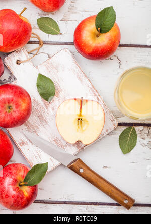 Bicchiere di fresco succo di mela biologico con pink lady mele rosse sul tagliere di legno su sfondo. Foto Stock