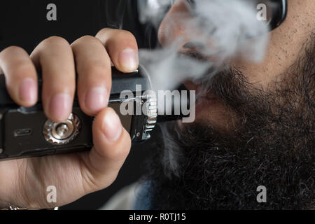 Close up di un irriconoscibile giovane uomo fumo da una penna vape o vaporizzatore Foto Stock