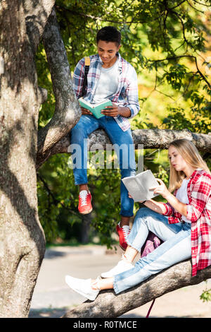 Gli studenti teen giovane rilassante sulla struttura e la lettura di libri Foto Stock