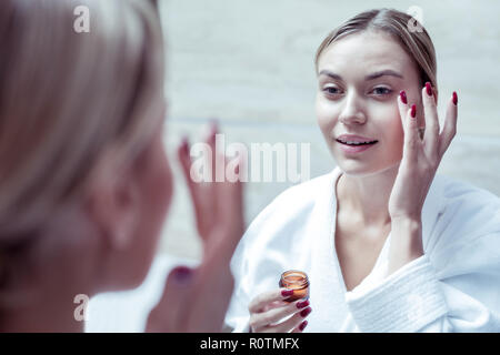 Bionda donna rimuovendo il suo trucco dopo una lunga giornata di lavoro Foto Stock