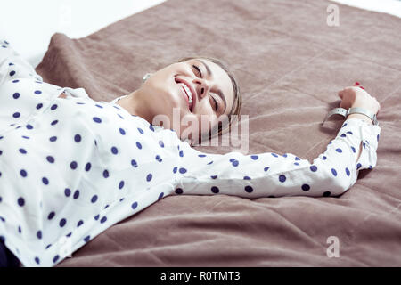 Bella sorridente imprenditrice avente il resto sul letto in hotel Foto Stock
