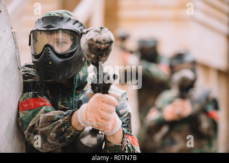 Paintballer maschio in maschera goggle coperti da paintball splash mirando dalla pistola di marcatore all'aperto Foto Stock