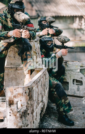 Il paintball giocatori puntando con marcatore cannoni da broken auto all'aperto Foto Stock