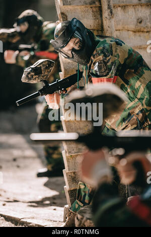 Messa a fuoco selettiva di paintball femmina player in camuffamento e la maschera protettiva azienda pistola marcatore all'aperto Foto Stock