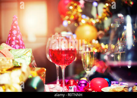 Rosso bicchieri da champagne sul tavolo con confezioni regalo e gli accessori di altri produttori con sfocato bokeh sfondo luminoso. Buon Natale e Felice Anno Nuovo celebrati Foto Stock