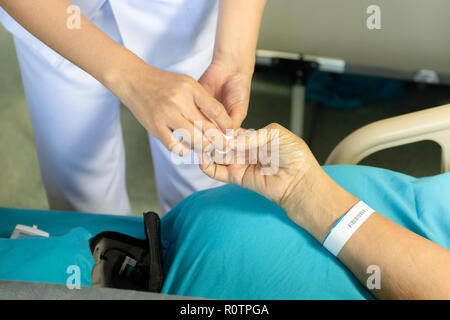 Infermiere con lana di cotone arrestare sanguinamento dal campione di sangue da un dito. Foto Stock