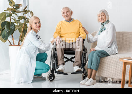 Giovane medico donna seduta con pazienti anziani in clinica Foto Stock